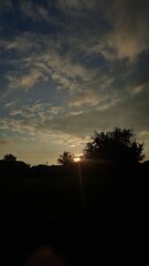 The sun sets in winter behind a house in the countryside.