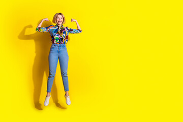 Full size photo of pretty young girl jump flexing muscles wear trendy colorful outfit isolated on yellow color background