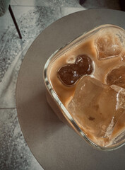 Ice coffee latte in stone table.  Ice coffee served in glass with coffee ice cubes and milk cream on table.