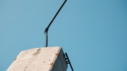 Obraz premium Low-angle view of a weathered concrete utility pole with attached cable against a clear sky
