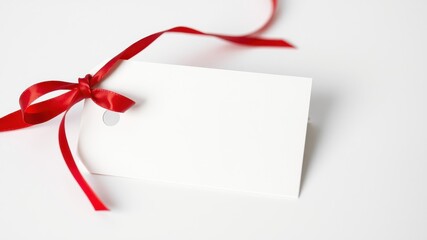 Blank white gift tag adorned with a crimson ribbon bow, ready for a personalized message