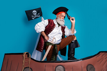 Obraz premium Photo of pensive thoughtful pirate wearing traditional costume swimming in boat isolated on blue color background