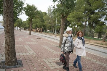 Two middle-aged women strolling through the center of a small Spanish town on a cold winter day