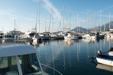 Fototapeta premium Picturesque Harbor with Boats and Mountain Village. The calm water reflects the surrounding architecture and hills, creating a peaceful coastal atmosphere. High quality photography