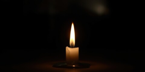 A single candle flame illuminates the darkness, a beacon of hope and remembrance