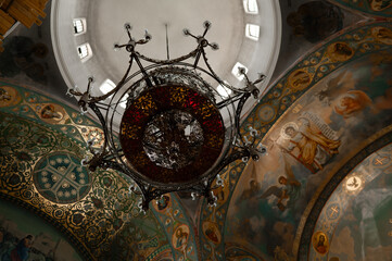a large beautiful chandelier against the background of frescoes in an Orthodox church