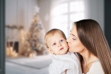 Loving mother carrying newborn baby at home.