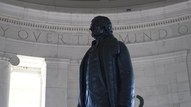 Closeup statue of Thomas Jefferson inside the Jefferson Memorial in Washington, D.C. The statue is made of bronze and stands tall against the white marble walls of the monument.