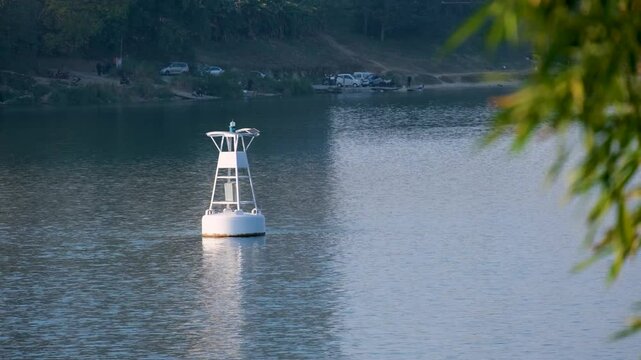a white navigation buoy floating on calm waters of the Liujiang River in Liuzhou, China.A peaceful urban waterscape typical of Southern China's river systems.