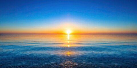 Obraz premium Sunrise over calm ocean with clear blue sky