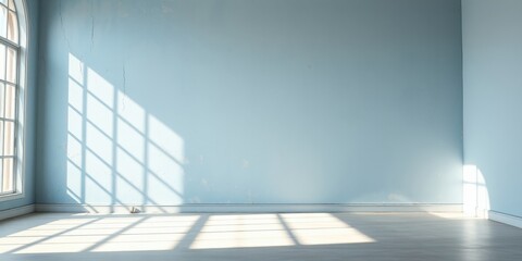 Obraz premium Empty room with light blue walls and sunlight streaming through a window