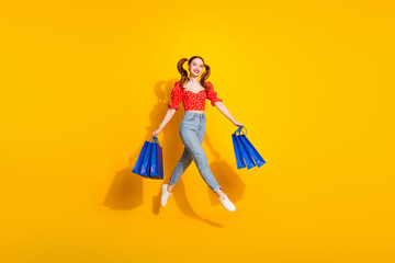 Full body photo of attractive young woman hold shopping bags jump runner dressed red retro clothes isolated on yellow color background