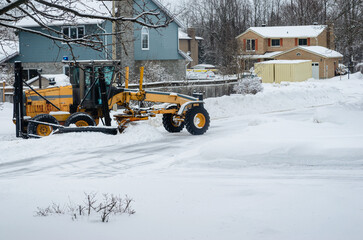 Motor Grader snowplow clearing a residential court