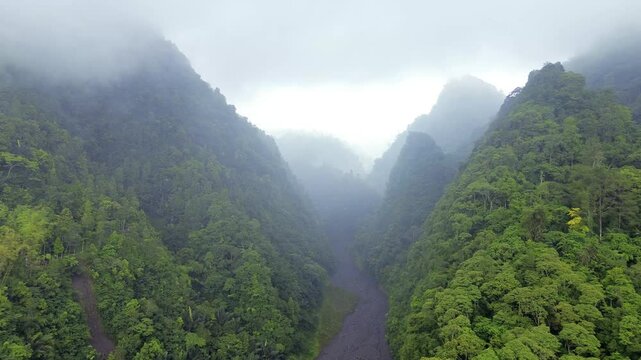 Dramatic Aerial Scene of Towering Mountain Peaks, Dense Rainy Forests  and Volcanic Lava Canyon in Foggy Weather