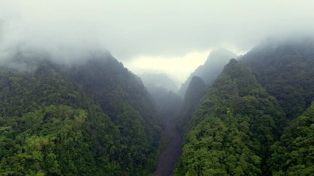 Dramatic Aerial Scene of Towering Mountain Peaks, Dense Rainy Forests  and Volcanic Lava Canyon in Foggy Weather
