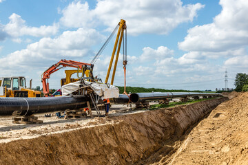 Kran hebt Rohr auf Baustelle zum Einschwei&szlig;en