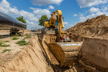 Obraz premium Bagger gräbt Graben für Rohrverlegung auf Baustelle