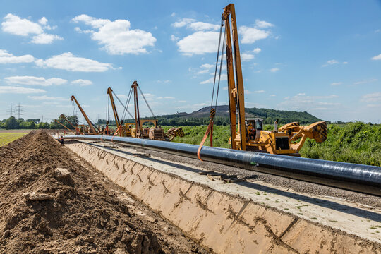 Rohrverlegung mit Kr&auml;nen auf Baustelle im Freien