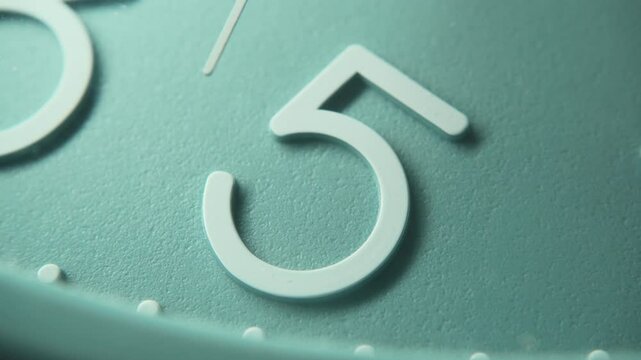 Number 5 on a blue wall clock with moving second hand. The time is five o'clock