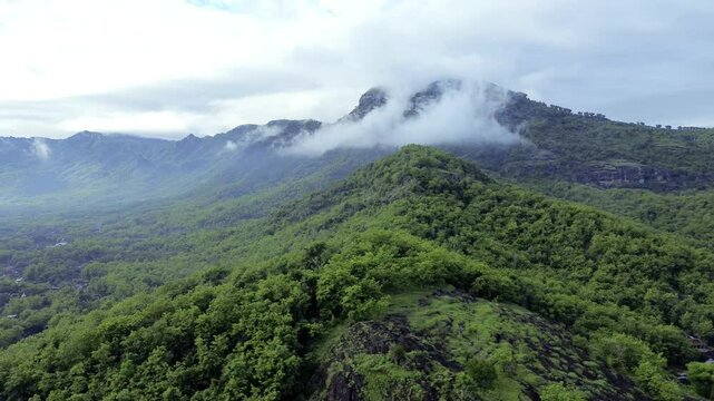 Aerial view of Misty Green limestone karst Mountains with Dense Forest and Rolling Clouds