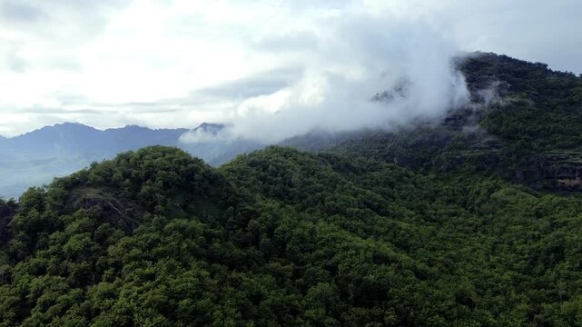 Aerial view of Misty Green limestone karst Mountains with Dense Forest and Rolling Clouds