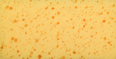 Yellow porous cleaning sponge texture close up background