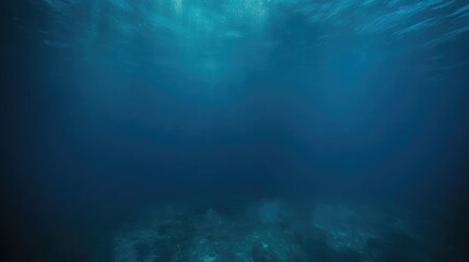 Cinematic underwater shot of deep blue ocean viewed from below. Camera angles up towards surface with faint light filtering through water, conveying vastness, depth, tranquility