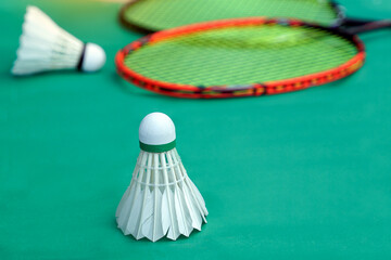 white shuttlecock on green background, blurred badminton racket and white shuttlecocks background. soft and selective focus