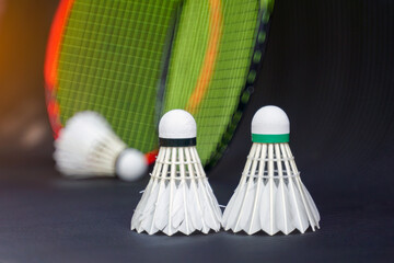 2 white shuttlecocks on black background, blurred badminton racket and white shuttlecocks background. soft and selective focus.