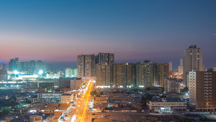 Cityscape with towers in Ajman from rooftop day to night timelapse. United Arab Emirates.
