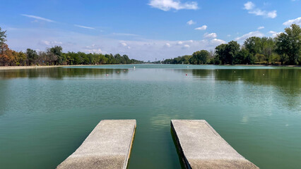 Concrete piers extending into a calm green lake under a clear blue sky, perfect for themes of nature, relaxation, and travel destinations.