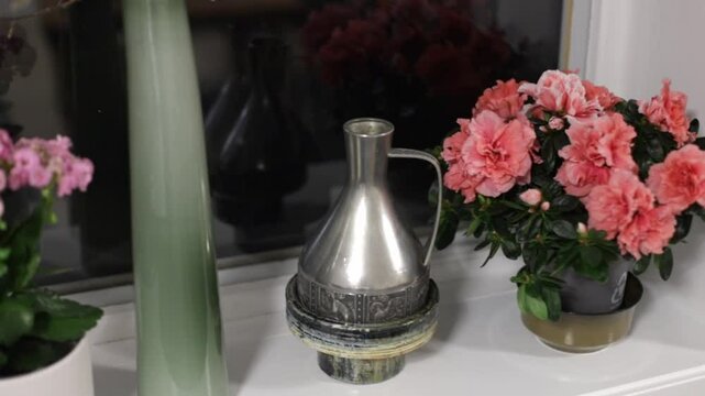 bright flowers grow on the windowsill azalea paradise at home antique vase on the windowsill iron vase on windowsill flowers in winter flowers in the dark house plants comfort home decoration