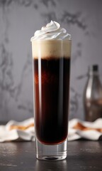 Tall glass filled with dark liquid and topped with a layer of creamy foam, wooden decor, dark liquid, cozy atmosphere