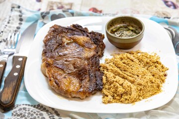 Typical Brazilian lunch with grilled steak, farofa and sauce