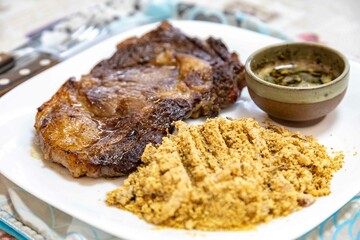 Typical Brazilian lunch with grilled steak, farofa and sauce