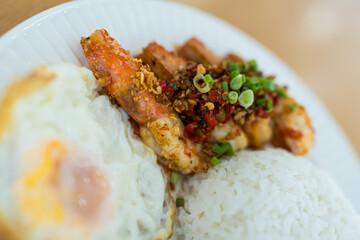 Stir fried shrimp with garlic and chili served together with steamed rice and find egg on white plate