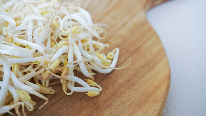 A pile of green and white sprouts on a wooden cutting board