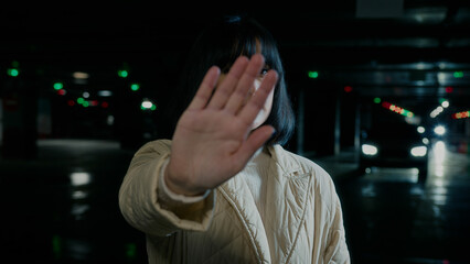 Sad strong angry hopless young Ukrainian Caucasian woman lady female girl showing stop enough gesture stretching palm anti war position no defense rejection distance sign in dark shelter parking lot
