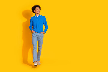 Naklejka premium Full size photo of pretty young male walking look empty space wear trendy blue outfit isolated on yellow color background