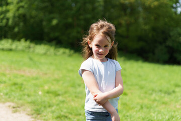 Little red-haired cute girl in summer outdoors in park. Concept of active healthy child in nature