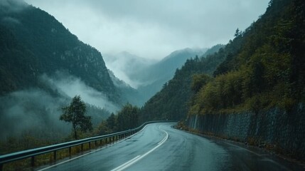 Winding road through misty mountain valley on a rainy day.
