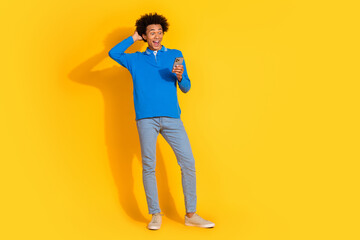 Full size photo of nice young man use smart phone empty space isolated on yellow color background