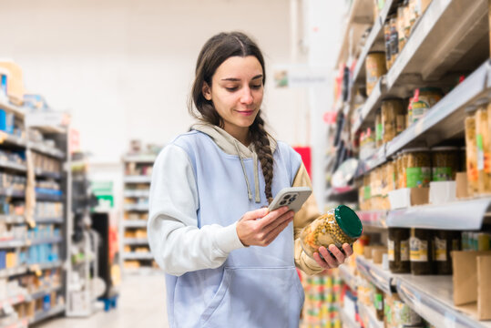 Woman using smartphone while shopping in grocery store