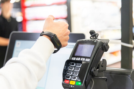 Anonymous hand's using payment terminal with smartwatch at supermarket