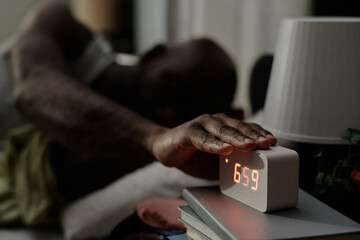 Unrecognizable male hand on alarm clock, he trying to stop in morning time