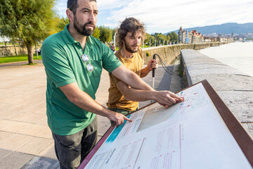 Blind man and friend exploring a location guide together