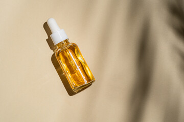 Cosmetic serum bottle on a beige background with shadow play