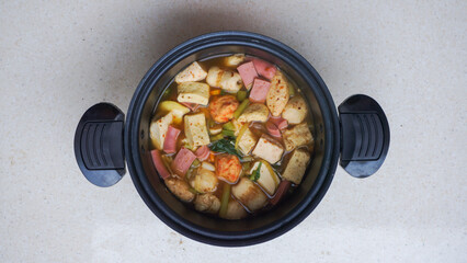 A bowl of soup with vegetables and meat in it.