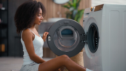 African American female woman girl ethnic lady housewife homeowner housework at floor open washing...