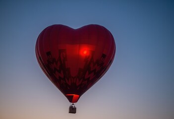 Fototapeta premium Heart-shaped hot air balloon glowing against twilight sky.